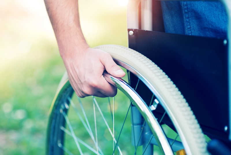 残疾人坐在轮椅上转动轮子前行
