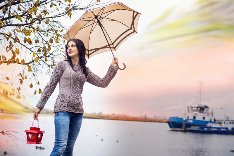 快乐的女人带着雨伞走在桥上