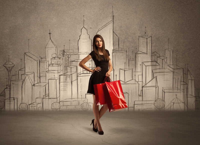 年轻女人手里拿着购物袋与绘制城市背景