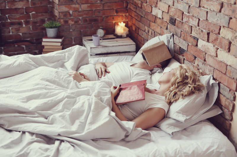 在床上看着书睡着的夫妇