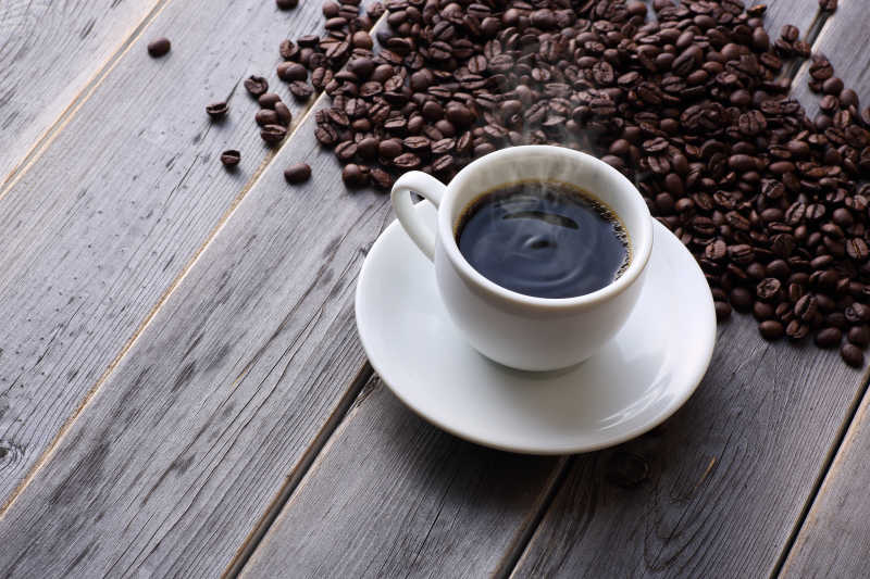 一杯放在木板上的香浓咖啡与咖啡豆