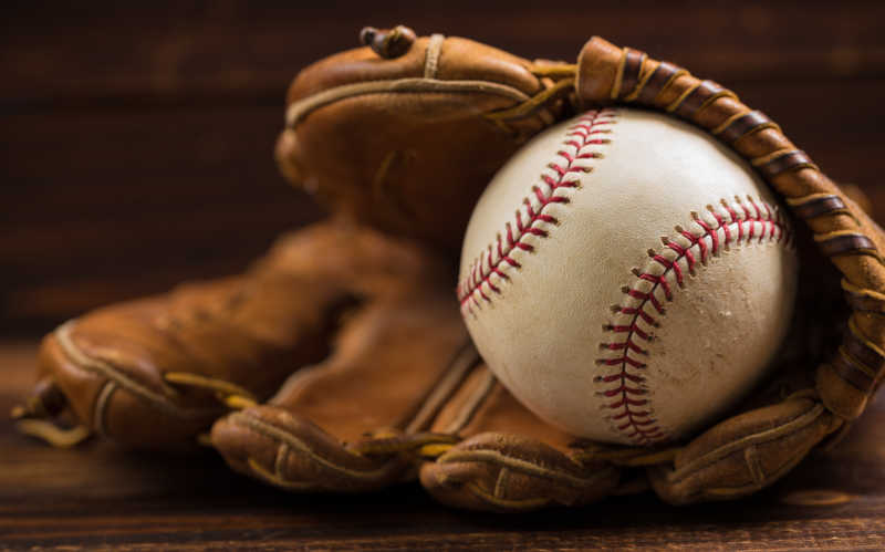 木长凳上的棕色棒球手套和棒球