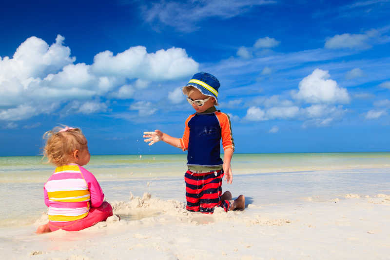 可爱的小男孩和小女孩在沙滩上玩沙子