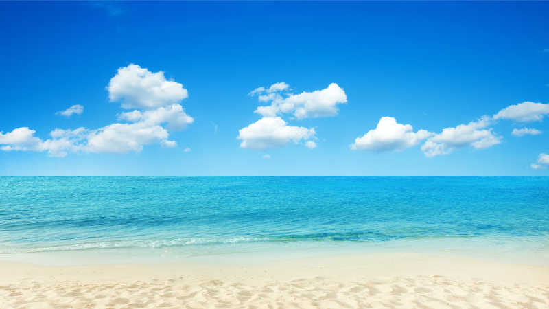 晴天有云的天空下的蓝色的大海和金色的沙滩