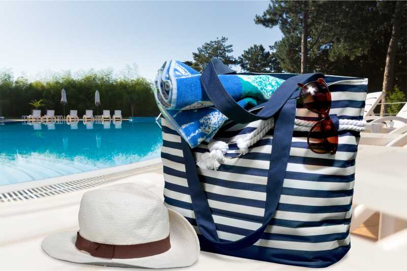 泳池边的购物袋和遮阳帽