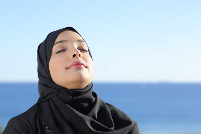 阿拉伯沙特妇女在海滩上呼吸着清新的空气
