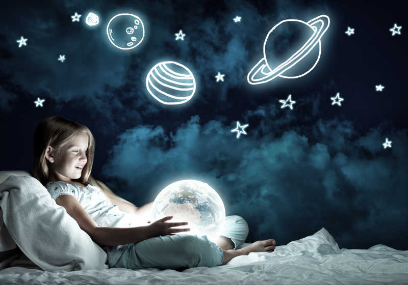女孩在她的床上触摸着发光的地球仪