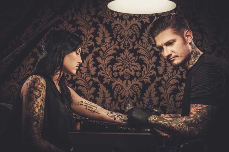 专业纹身师和年轻女孩的手臂纹身