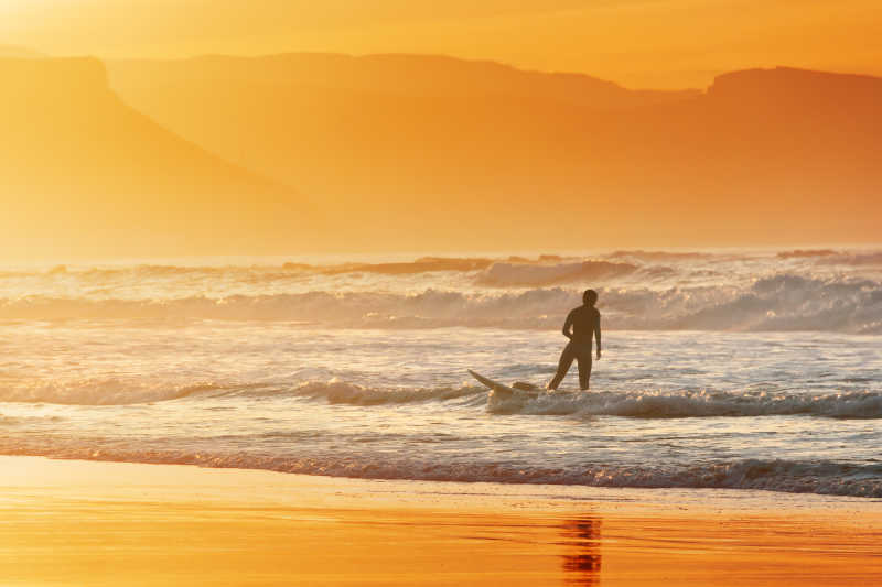 日落时分海滩上的冲浪者