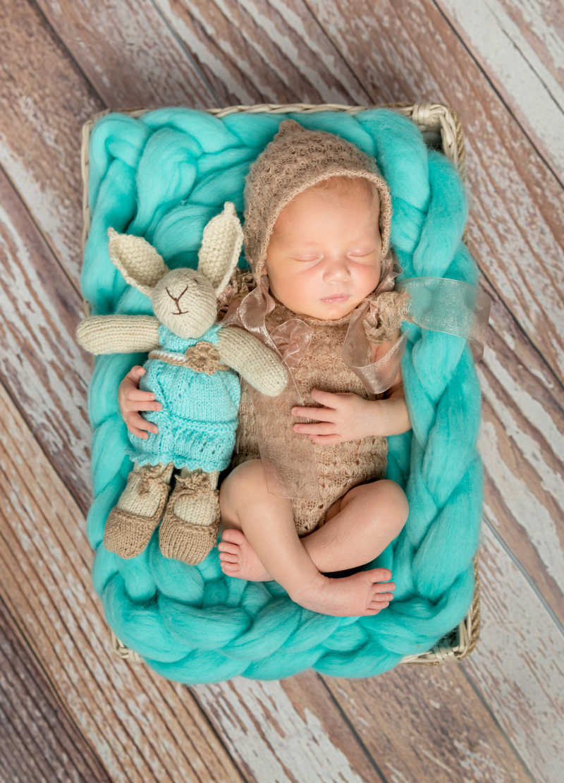 床上抱着兔子玩具可爱的新生婴儿