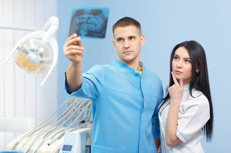 男性牙科医生和女性助理在看X光照片