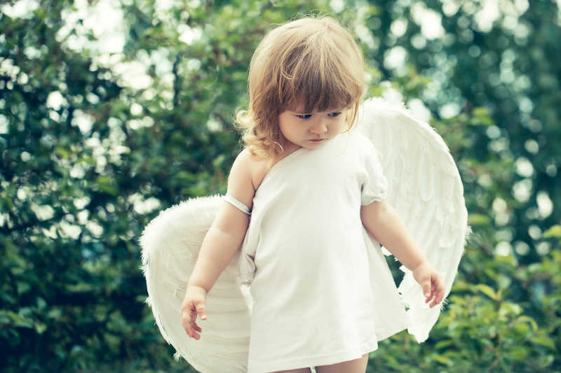 花园里可爱的带天使翅膀的男孩