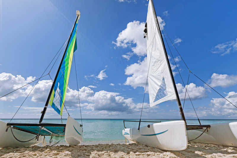 蓝天白云下停放在沙滩上的白色帆船