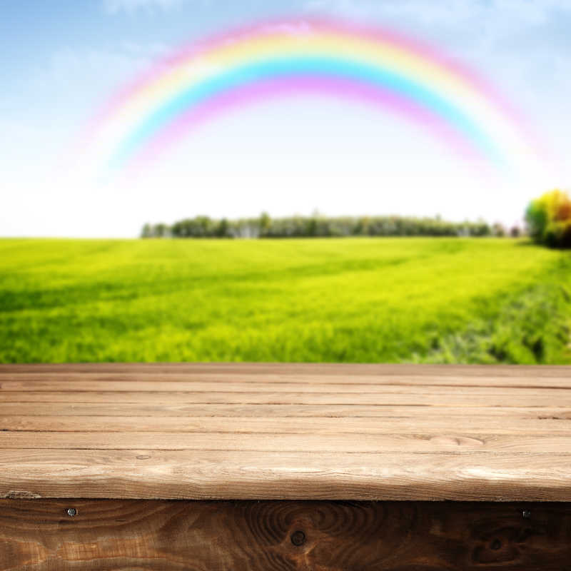 彩虹下的绿色田野背景前的书桌