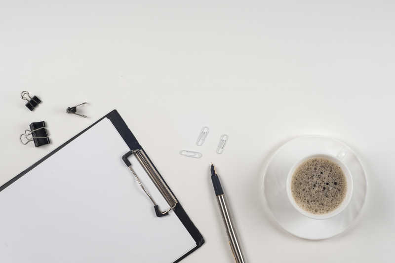 白色办公桌上的文件夹纸张钢笔和咖啡杯