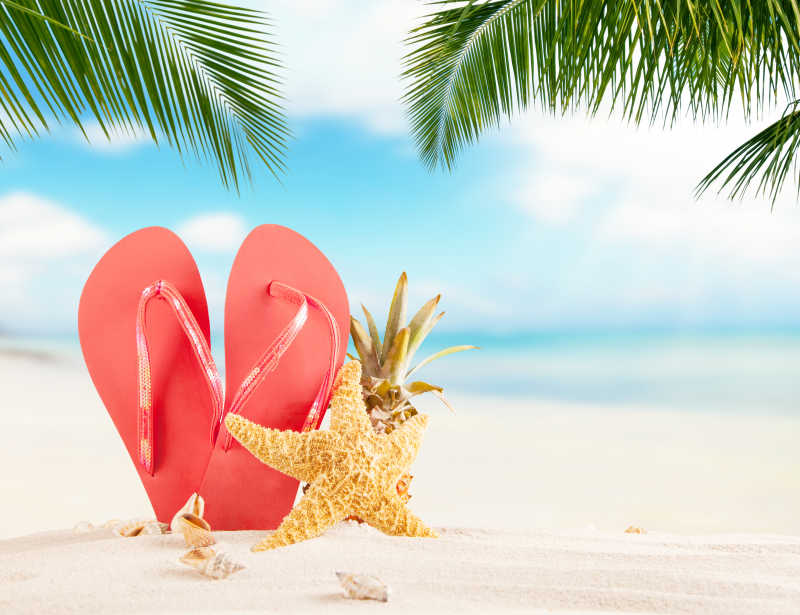 夏日沙滩上的红色拖鞋和海星