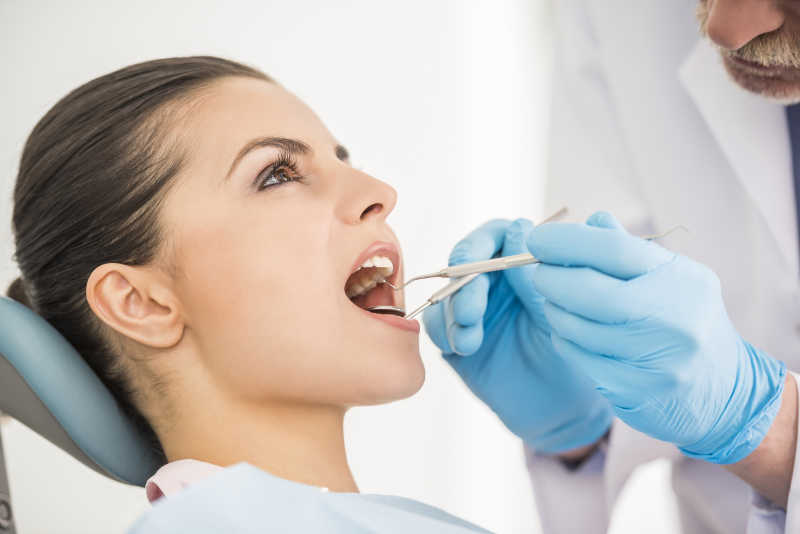 牙医为年轻美女检查牙齿