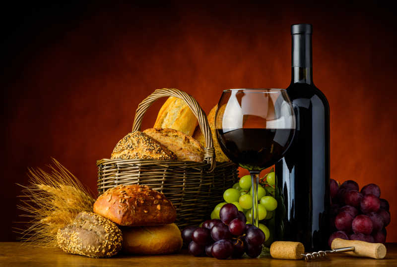 瓶装和杯中的红酒搭配一篮面包和葡萄