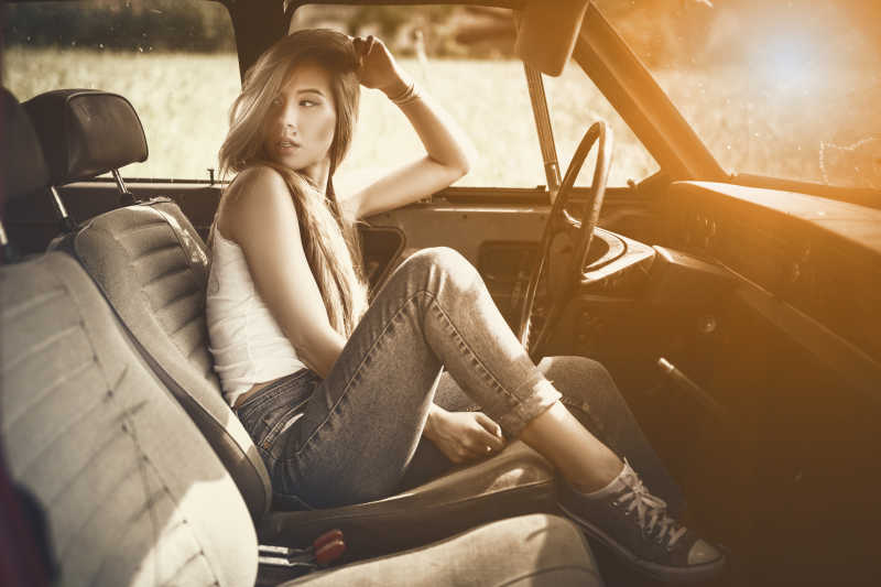 复古滤镜下坐在车里的时尚年轻女性