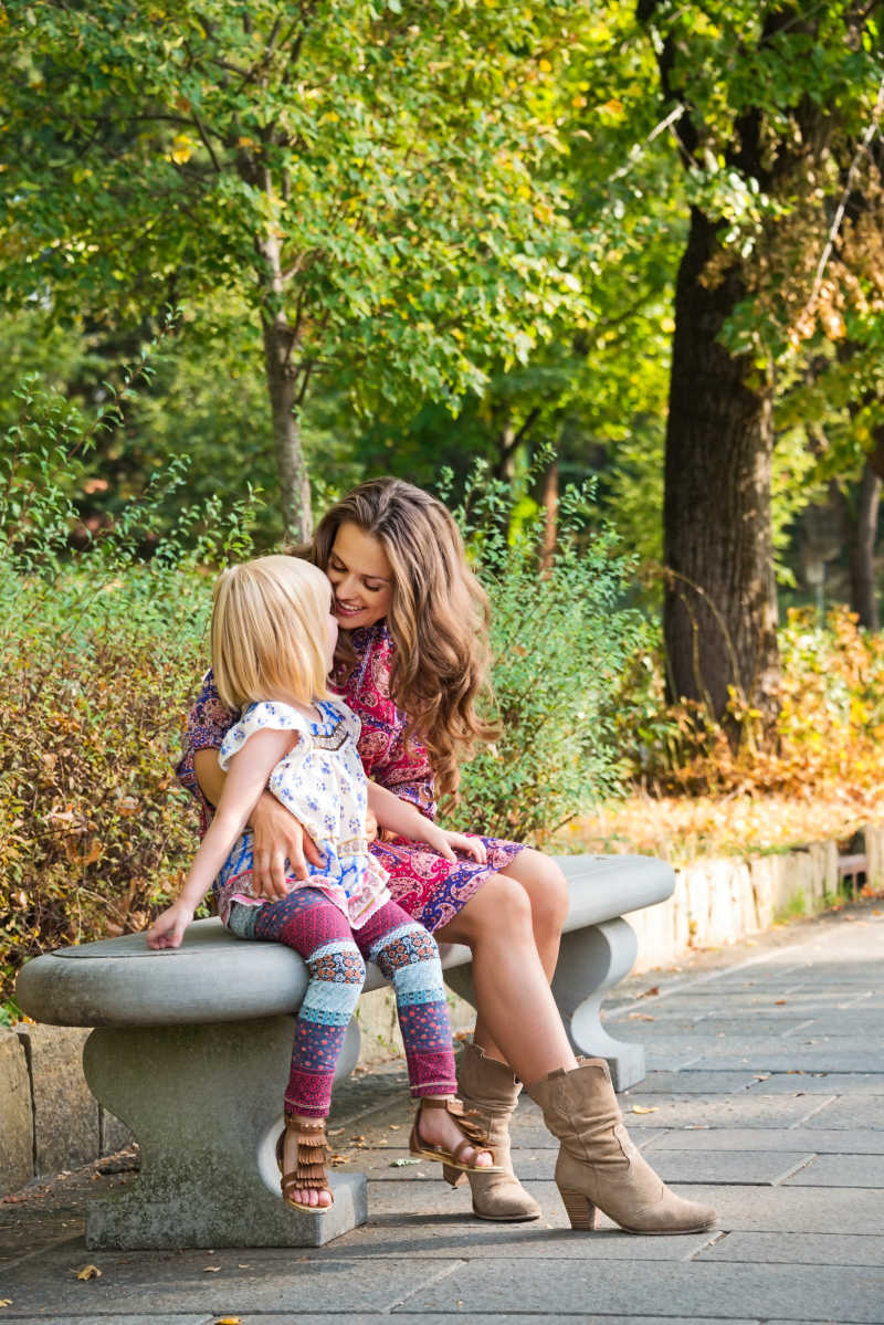 妈妈和小女孩开心的坐在长凳交流