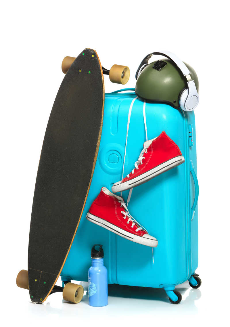 白色背景下靠着滑板挂着红色运动鞋的蓝色行李箱