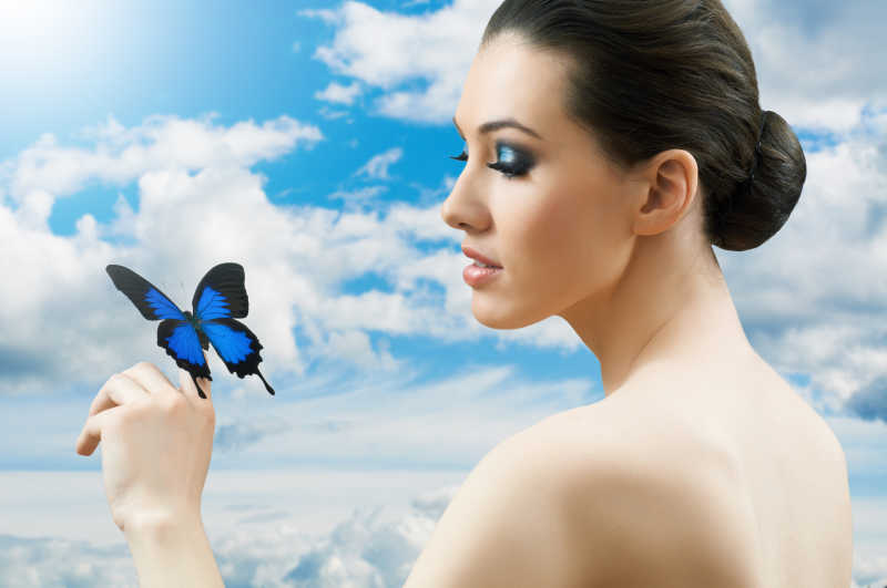 画蓝色眼影的女人看着蓝色蝴蝶