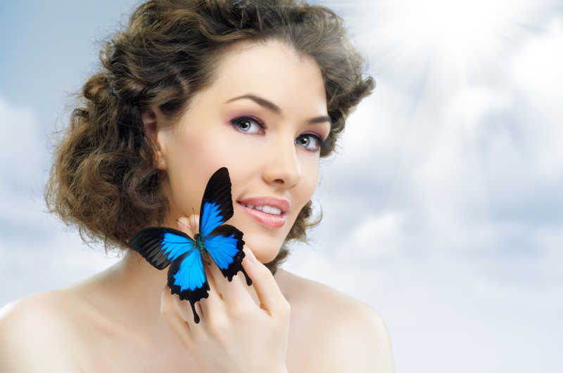 卷发女人手上有一种美丽的蓝蝴蝶