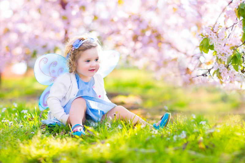 天使打扮的小女孩坐在花园里