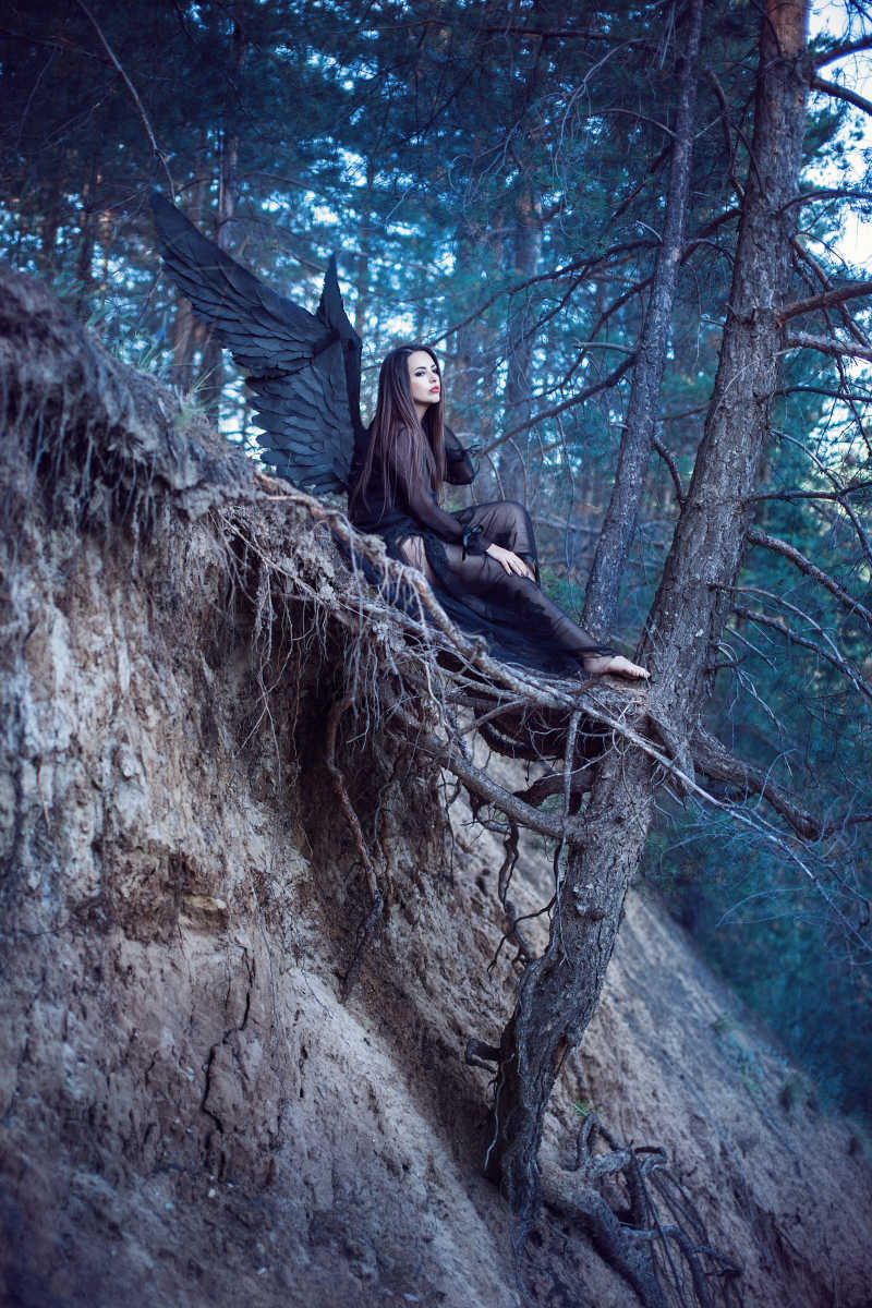 美丽的黑天使坐在森林里