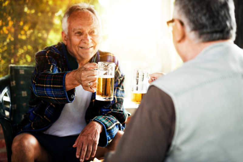 坐着喝啤酒干杯的两位老人