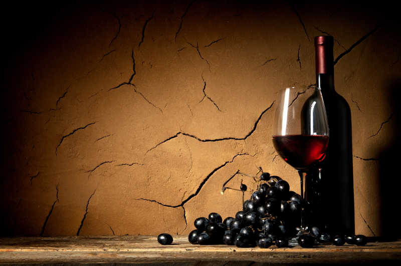窖壁背景下成熟的葡萄和葡萄酒