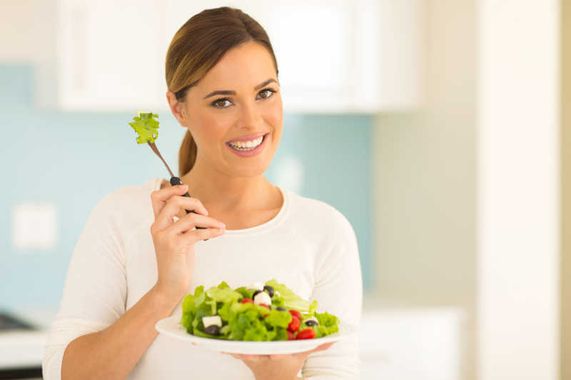 漂亮女人在家厨房吃蔬菜沙拉