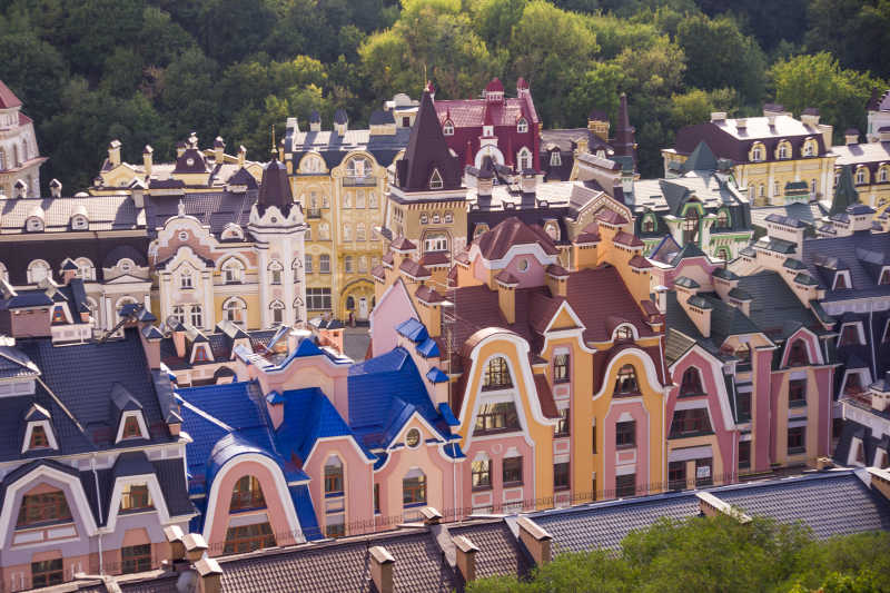 蓝天下绿色树木背景下的基辅乌克兰夏季的小型彩色建筑