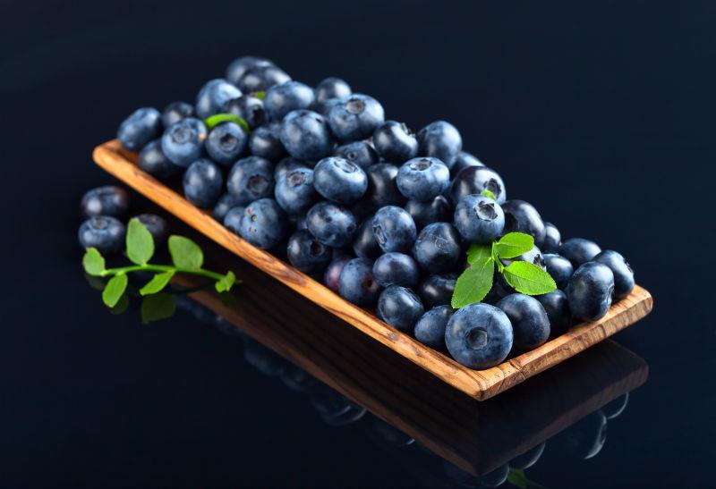 黑色背景下木盘中的蓝莓