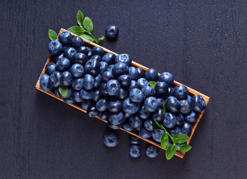 老木板上带绿叶的蓝莓