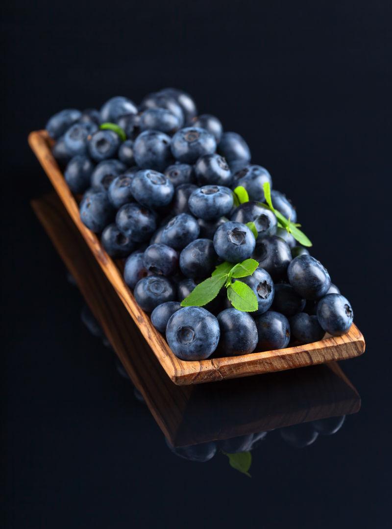 黑色背景下木盘里的蓝莓