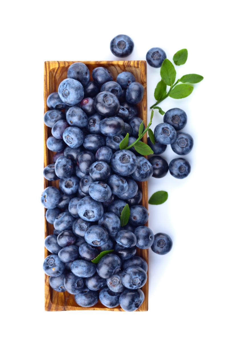 白色背景下木盘里的蓝莓