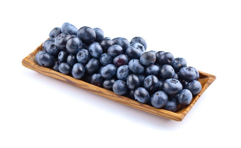 白色背景下一木盘的蓝莓