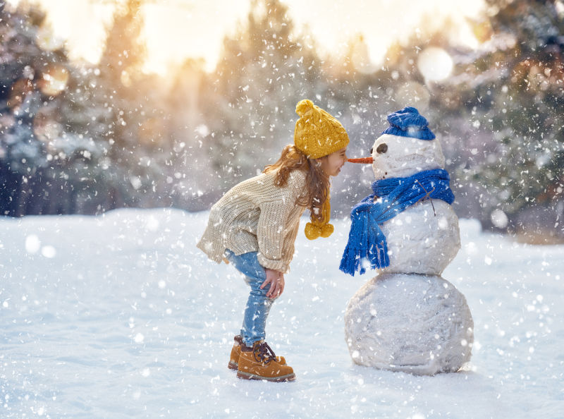 快乐的女孩在雪地上漫步雪人