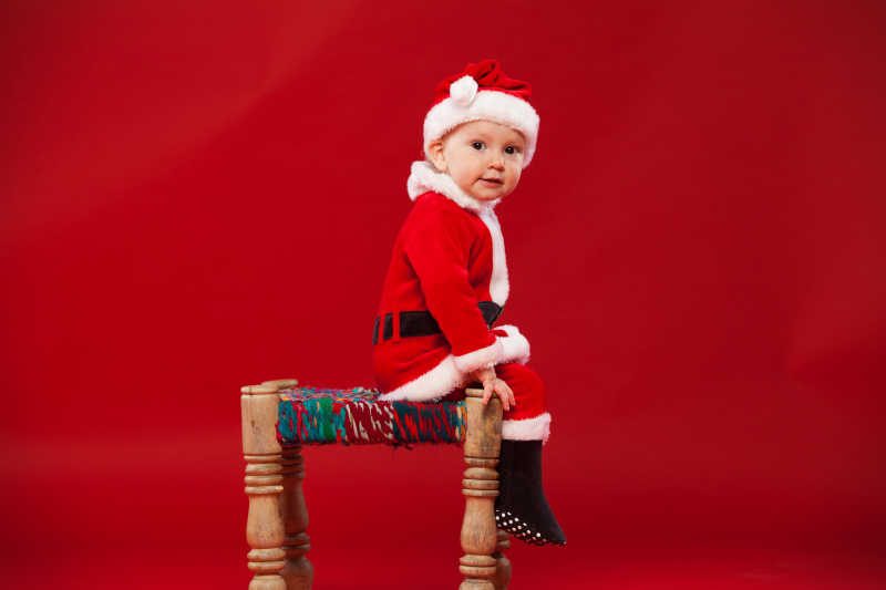 坐在椅子上可爱的孩子穿着圣诞衣服