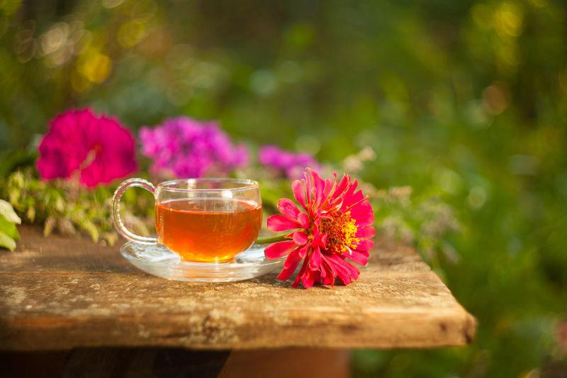 户外放在木桌上的鲜花和一杯绿茶
