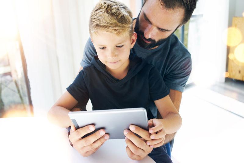 父亲和他的小儿子一起玩平板电脑