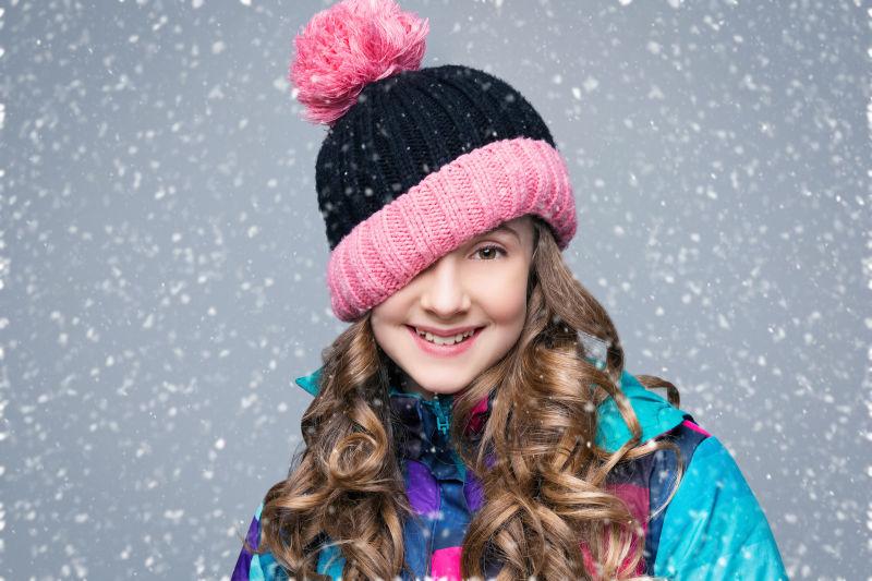 雪中戴着帽子的留着长卷发的小女孩