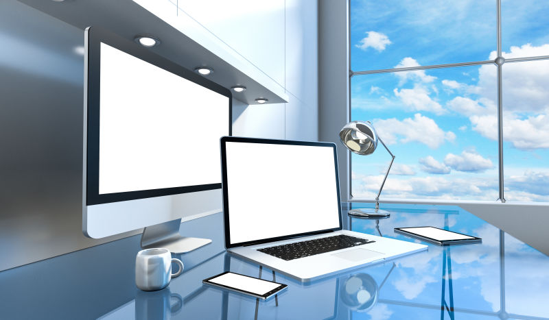 现代玻璃办公桌上的电脑和通讯设备