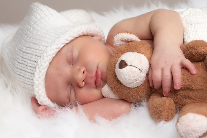 睡着的新生儿抱着可爱玩具熊