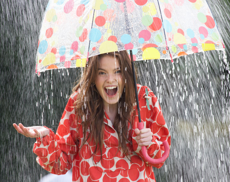 大雨中撑着彩色波点雨伞的少女