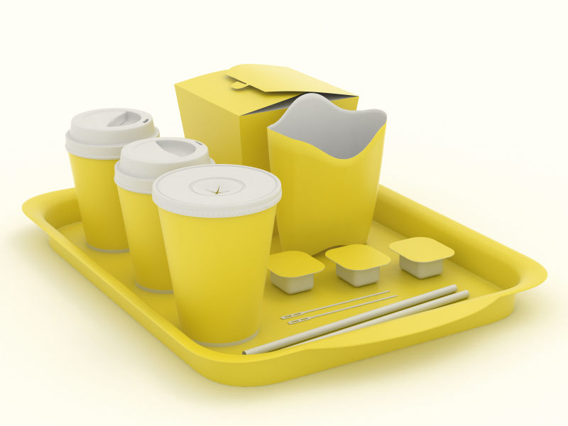 单色背景上放在托盘里的黄色快餐餐具模型
