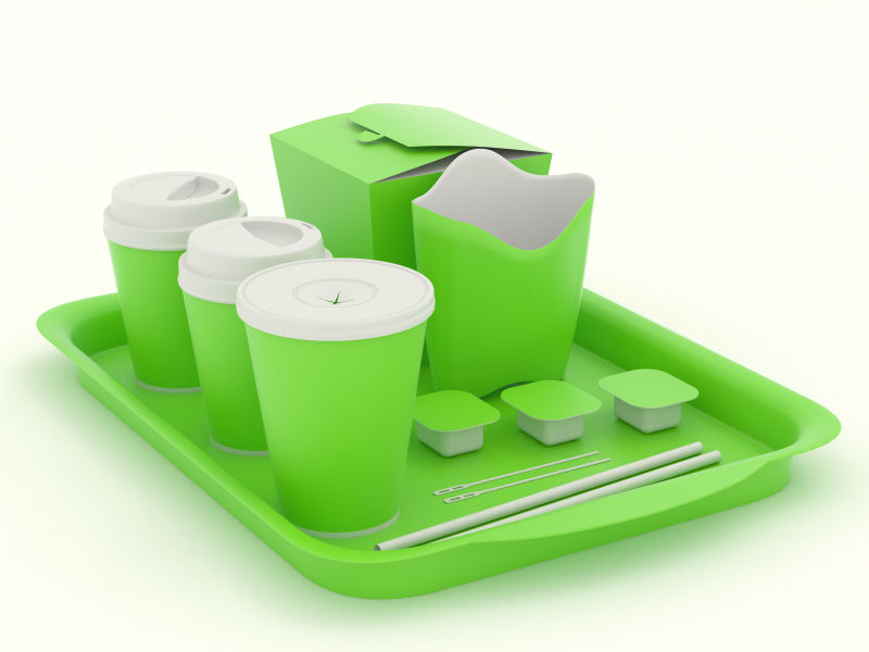 单色背景上放在托盘里的绿色快餐餐具模型