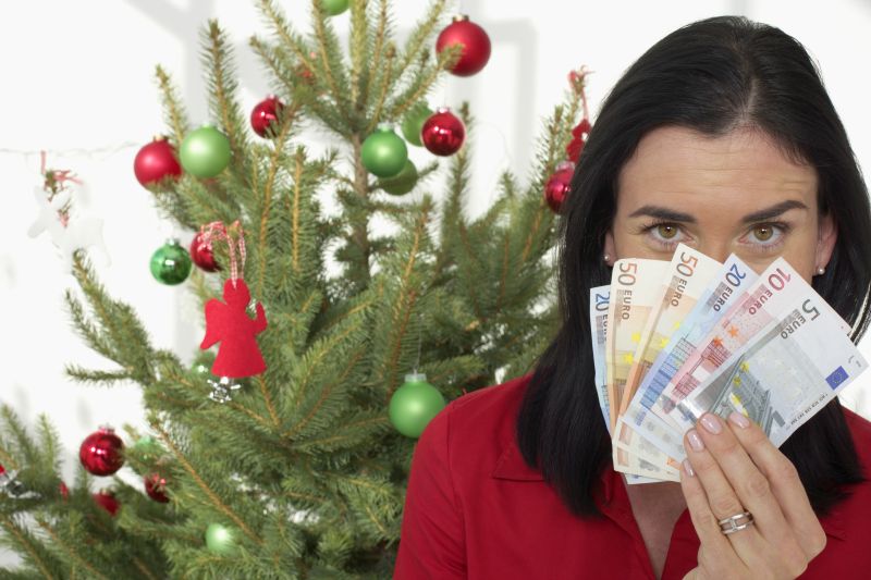 美女拿着欧元站在圣诞树前面