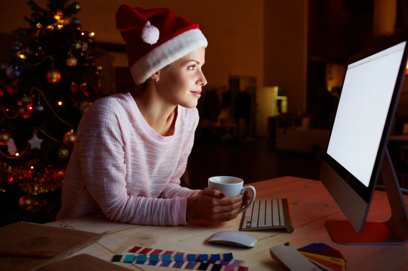 电脑屏幕前一个戴着圣诞帽的年轻女孩
